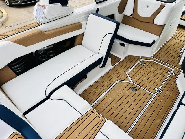 Slide: The Image of 2024 Nautique G23 boat interior with white and tan seating, teak flooring. - 29