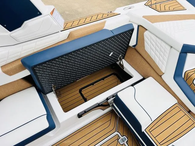 Slide: The Image of 2024 Nautique G23 boat interior with open storage compartment, featuring blue and tan seating. - 39