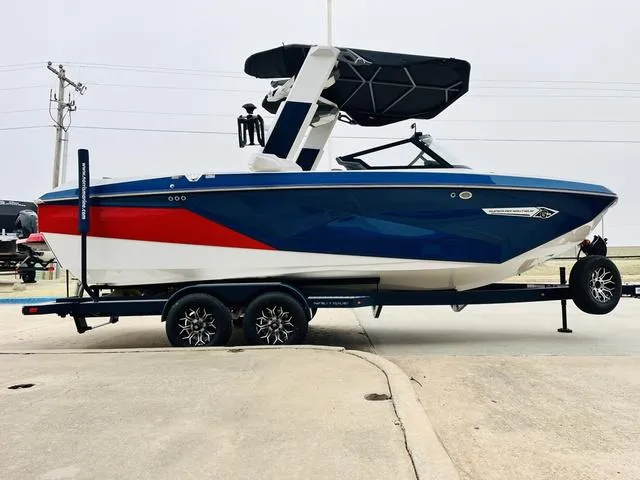 Slide: The Image of 2024 Nautique G23 boat with blue, red, and white design on a trailer. - 4