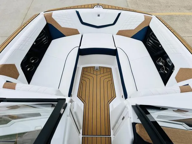 Slide: The Image of 2024 Nautique G23 boat interior with white and tan seating, wood accents, and cup holders. - 16