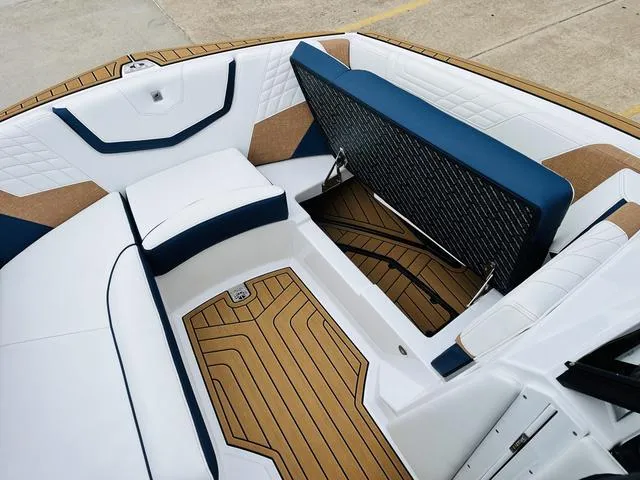 Slide: The Image of 2024 Nautique G23 boat interior with blue and white seating and teak flooring. - 18
