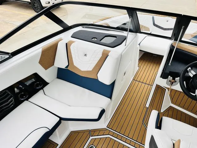 Slide: The Image of 2024 Nautique G23 boat interior with white and blue seating, teak flooring, and modern design. - 24