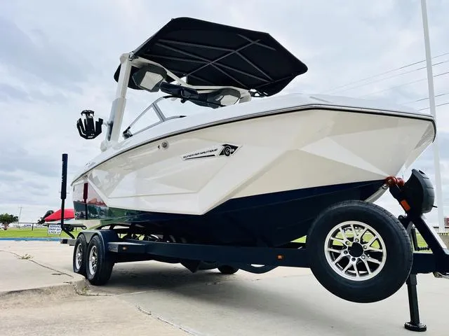 Slide: The Image of 2024 Nautique G23 boat on trailer, sleek design, white exterior, overcast sky. - 3