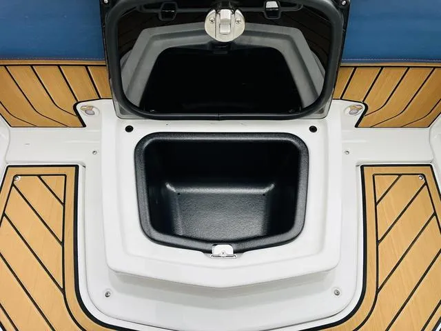 Slide: The Image of 2024 Nautique G23 storage compartment with open lid on teak deck. - 39