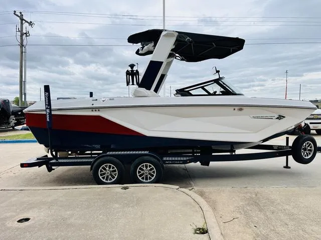 Slide: The Image of 2024 Nautique G23 boat on trailer, white and red design, parked outdoors. - 4