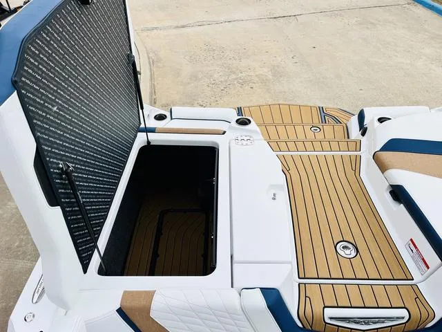 Slide: The Image of 2024 Nautique G23 boat with open storage compartment and teak-style deck. - 49