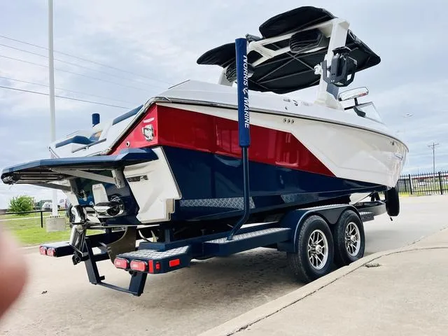 Slide: The Image of 2024 Nautique G23 boat on trailer, red and white design, parked outdoors. - 5