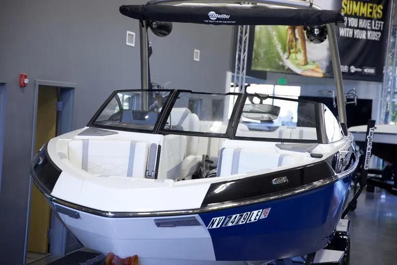 Slide: The Image of 2024 Malibu 23 LSV boat in showroom, sleek design, blue and white exterior. - 3
