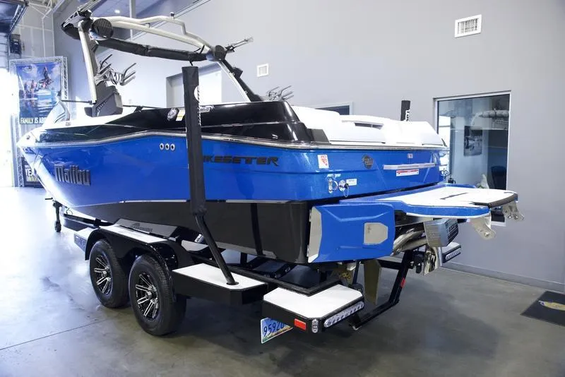 Slide: The Image of 2024 Malibu 23 LSV boat in showroom, blue and black design, on trailer. - 4