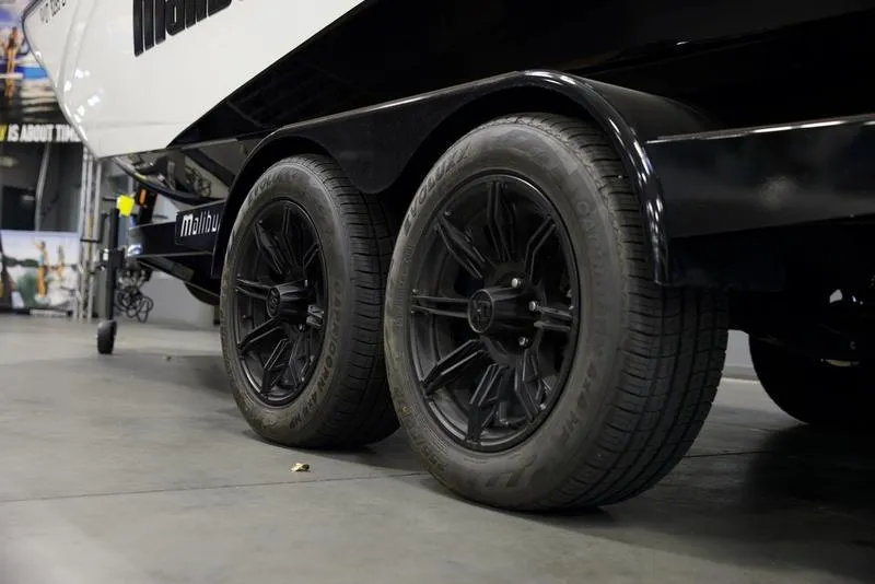 Slide: The Image of 2024 Malibu 23 LSV boat trailer with black wheels in a showroom. - 7