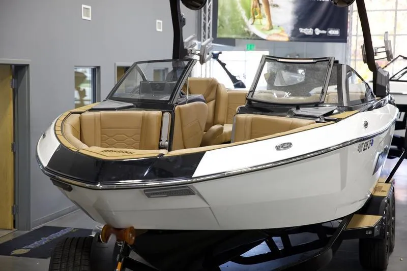 Slide: The Image of 2024 Malibu 23 LSV boat with tan interior on display indoors. - 9