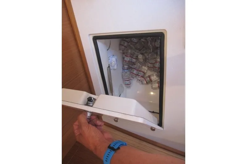 Slide: The Image of Opening a storage compartment filled with water bottles on a 2025 Catalina 386. - 25