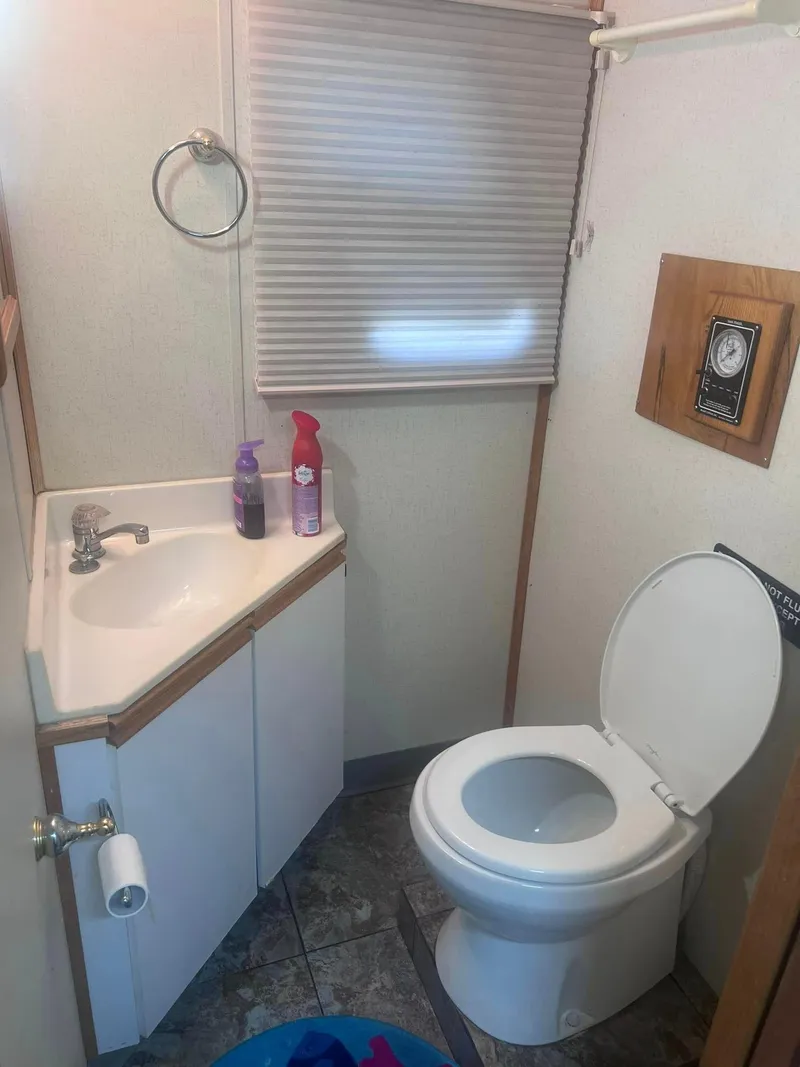 Slide: The Image of 1993 Fun Country houseboat bathroom with sink, toilet, and window shade. - 14