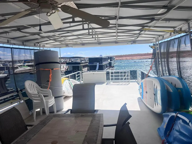 Slide: The Image of 1993 Fun Country houseboat deck with chairs, table, and paddleboards on a sunny day. - 21