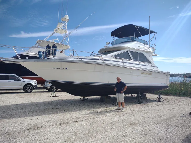 The Image of 1988 Sea Ray 345 Sedan Bridge yacht on stands, parked outdoors under a clear sky. - 0