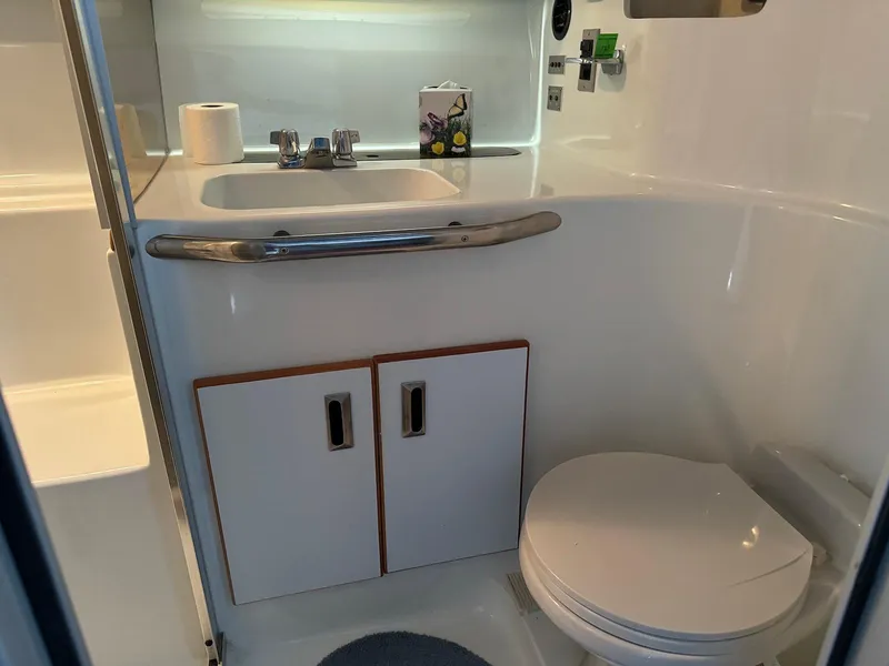 Slide: The Image of 1988 Sea Ray 345 Sedan Bridge bathroom with sink, toilet, and storage cabinets. - 15