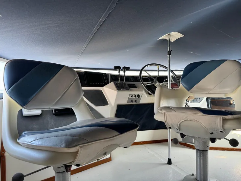 Slide: The Image of 1988 Sea Ray 345 Sedan Bridge helm with dual captain chairs and steering wheel. - 19