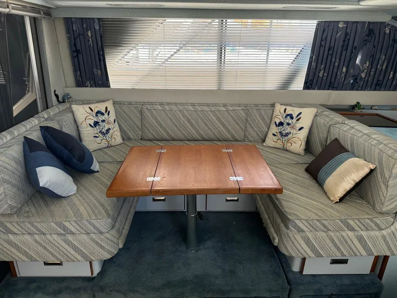 Slide: The Image of Interior of 1988 Sea Ray 345 Sedan Bridge with cozy seating and wooden table. - 3