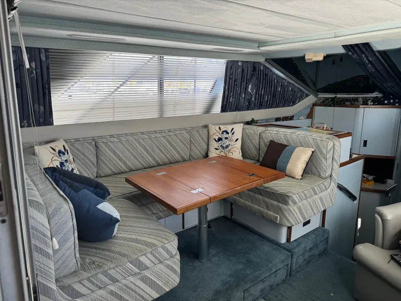 Slide: The Image of Interior of 1988 Sea Ray 345 Sedan Bridge with cozy seating and wooden table. - 4