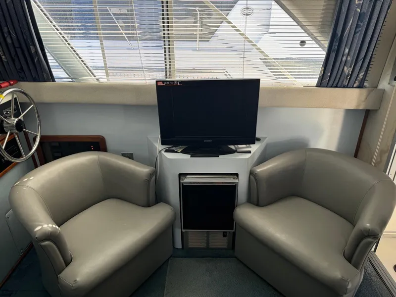 Slide: The Image of Interior of 1988 Sea Ray 345 Sedan Bridge with two chairs and a TV. - 5