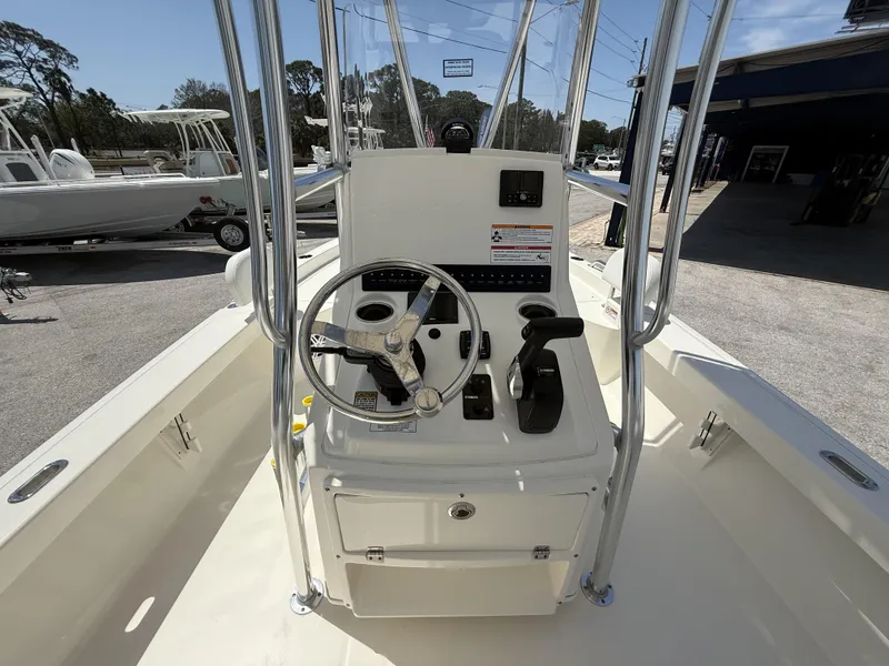 Slide: The Image of 2025 Pathfinder 2200 TRS boat console with steering wheel and controls, docked outdoors. - 11