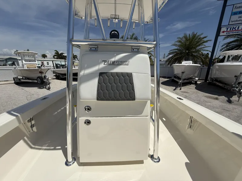 Slide: The Image of 2025 Pathfinder 2200 TRS boat interior with seating and console, sunny day, palm trees in background. - 36