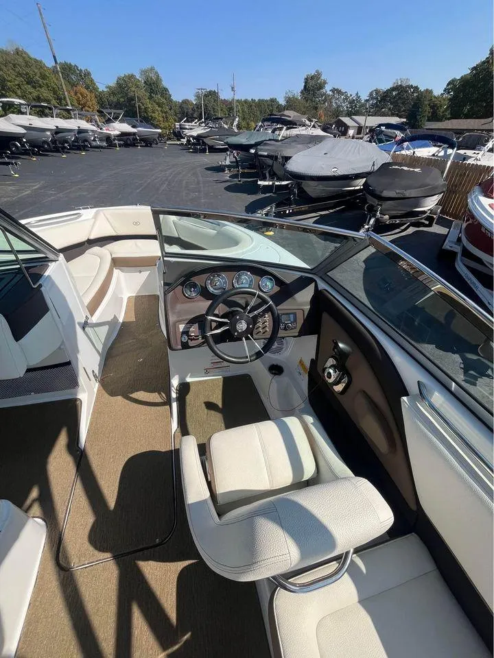 Slide: The Image of 2017 Cobalt 220S boat interior with steering wheel and dashboard, parked among other boats. - 3