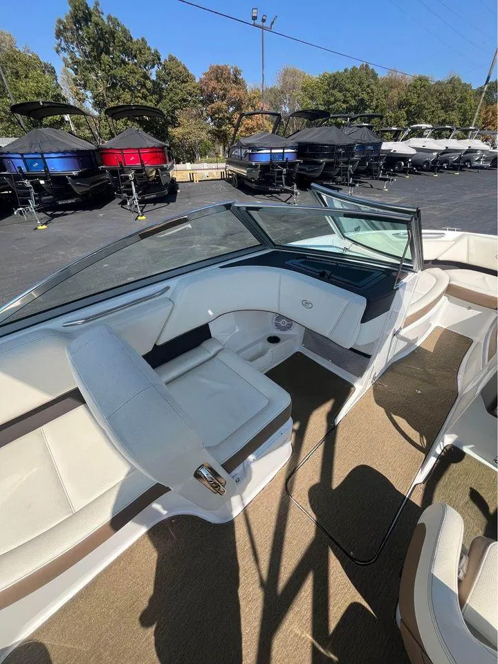 Slide: The Image of 2017 Cobalt 220S boat interior with white seating and dashboard, parked near other boats. - 4