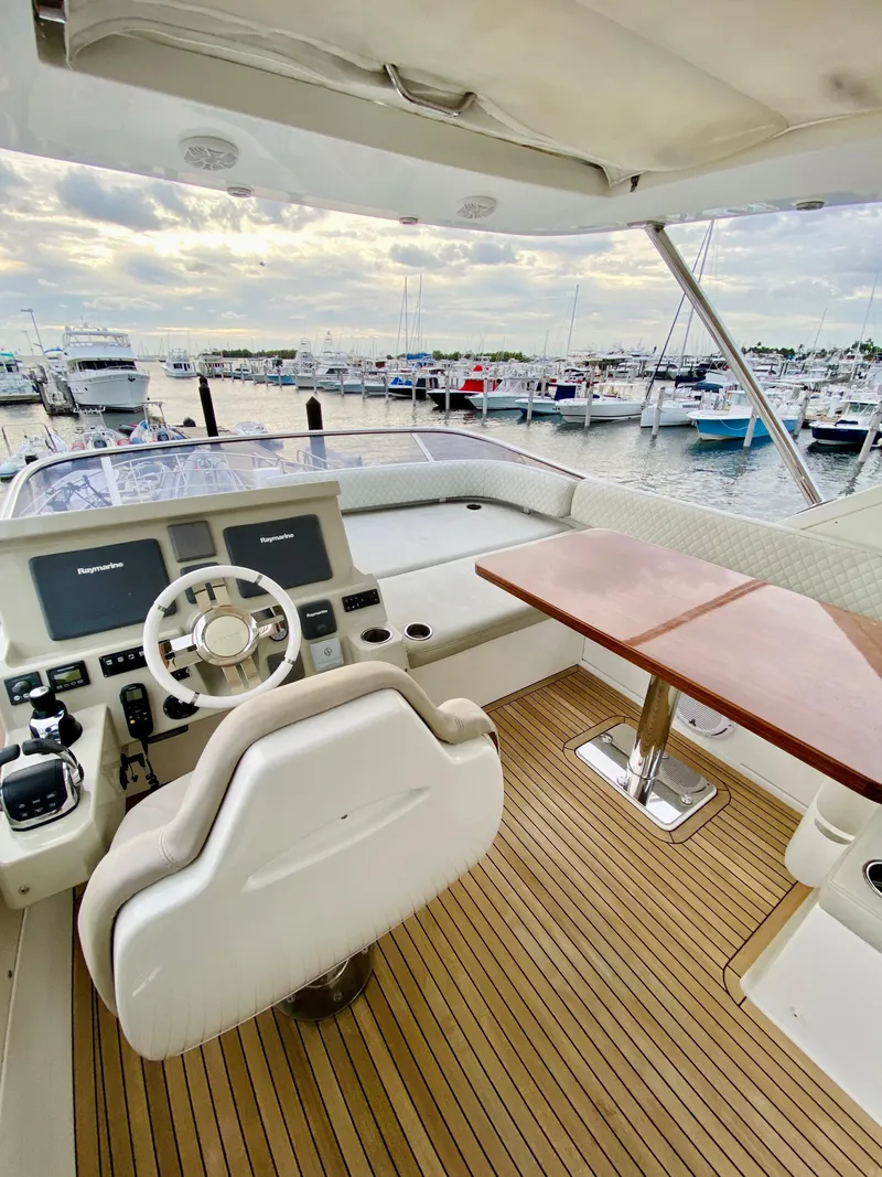 Slide: The Image of 2015 Azimut 50 yacht helm with marina view, featuring modern controls and wooden deck. - 22