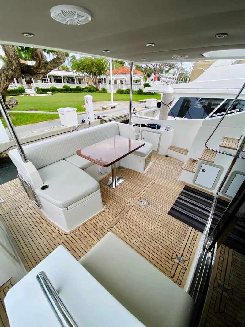 Slide: The Image of 2015 Azimut 50 yacht deck with seating and table, docked near lush greenery. - 7