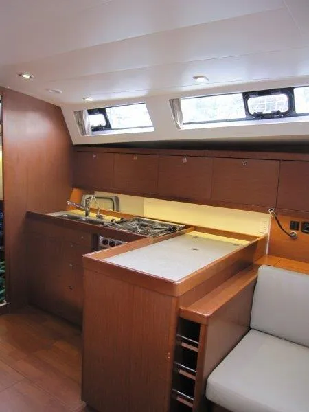 Slide: The Image of Interior of 2015 Beneteau Oceanis 45 yacht, featuring a modern kitchen with wood cabinetry. - 16