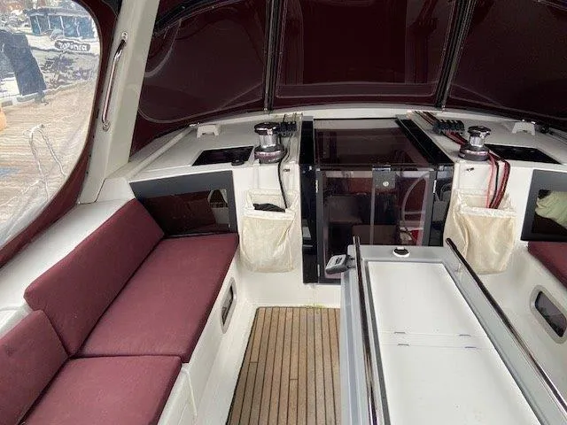 Slide: The Image of Interior of 2015 Beneteau Oceanis 45 sailboat with maroon seating and wood flooring. - 26