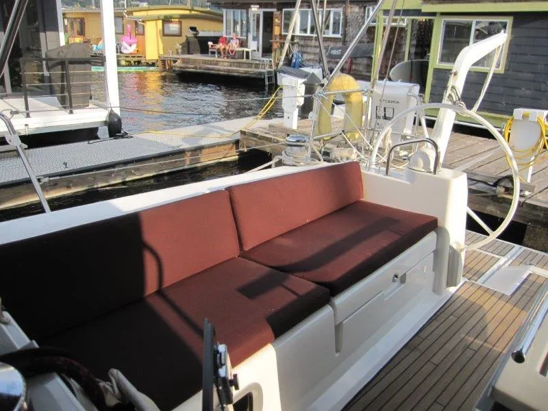 Slide: The Image of Beneteau Oceanis 45 sailboat cockpit with brown cushions, docked near houseboats, 2015 model. - 29