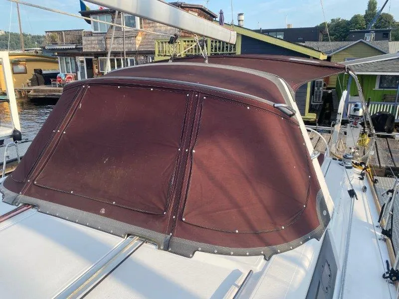Slide: The Image of 2015 Beneteau Oceanis 45 sailboat with maroon canopy docked near waterfront homes. - 41