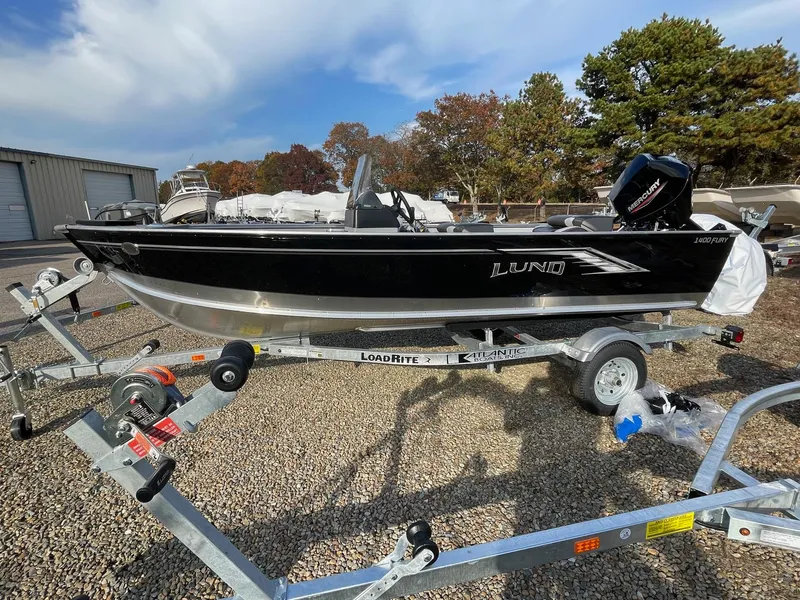 Slide: The Image of 2025 Lund 1400 Fury SS boat on trailer, parked outdoors. - 0