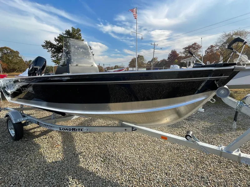 Slide: The Image of 2025 Lund 1400 Fury SS boat on trailer, displayed outdoors under a clear sky. - 1
