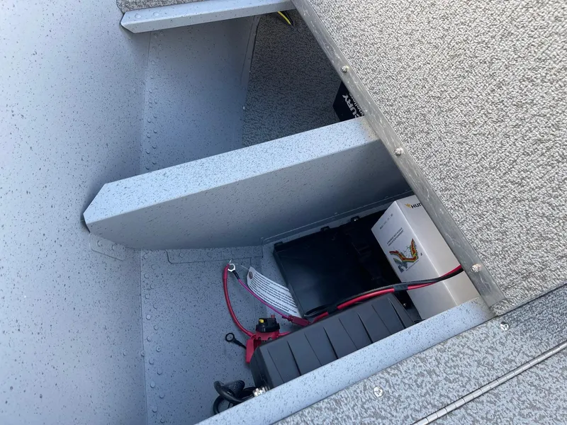 Slide: The Image of 2025 Lund 1400 Fury SS boat storage compartment with battery and wiring. - 10