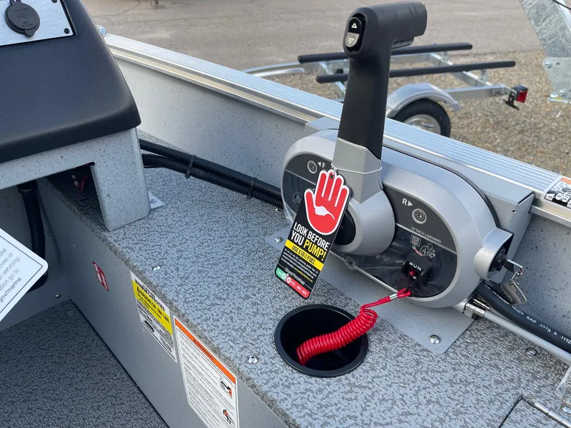 Slide: The Image of 2025 Lund 1400 Fury SS boat throttle control with safety warning tag. - 11