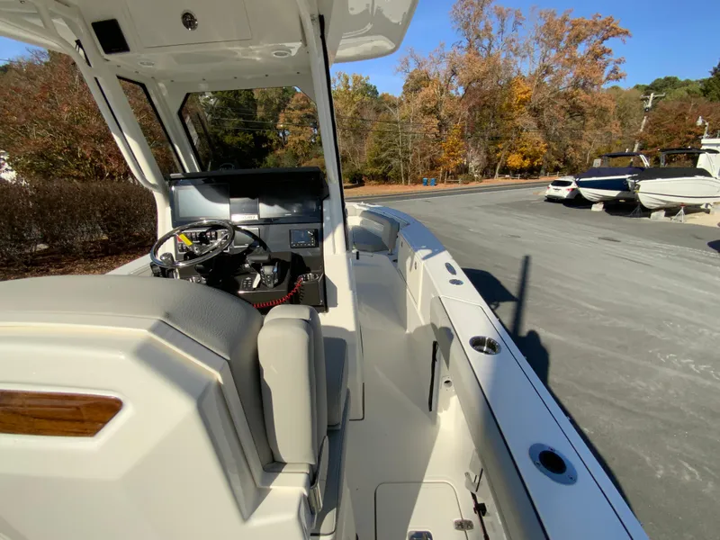 Slide: The Image of 2025 Pursuit S 248 Sport boat interior with steering console, parked outdoors. - 17