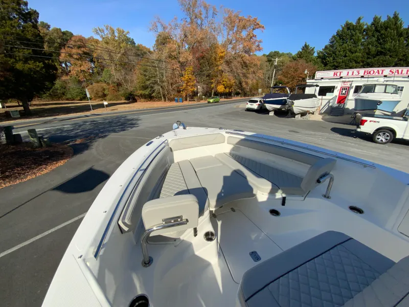 Slide: The Image of 2025 Pursuit S 248 Sport boat at dealership, surrounded by autumn trees. - 27