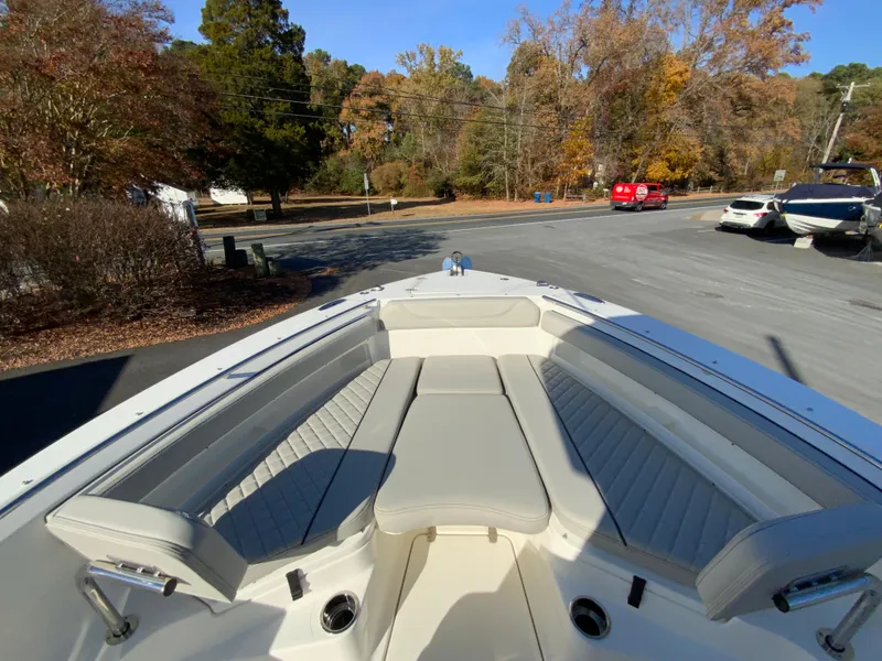 Slide: The Image of 2025 Pursuit S 248 Sport boat interior with cushioned seating, parked outdoors. - 28