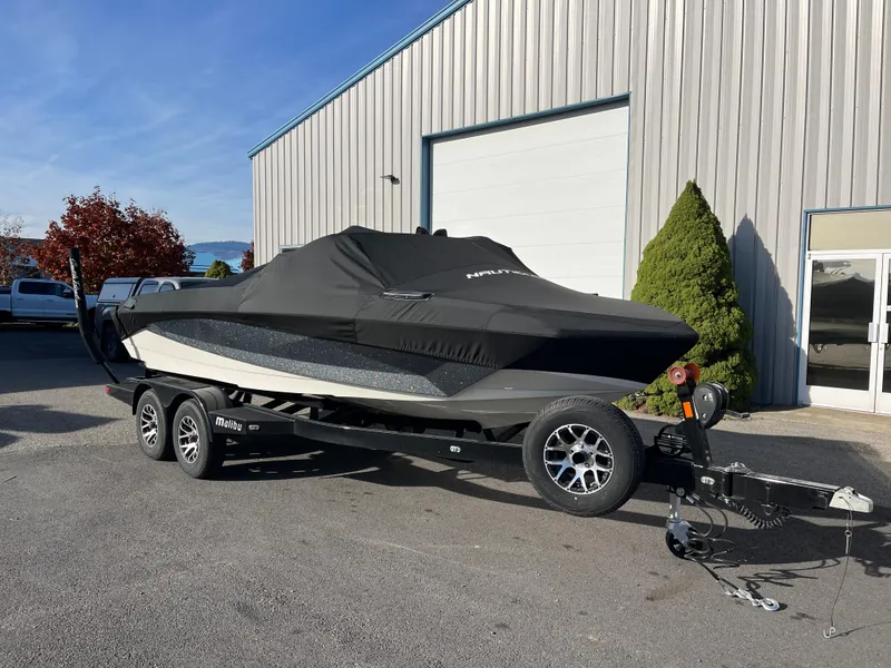 Slide: The Image of 2024 Nautique Ski Nautique boat covered on trailer outside a warehouse. - 22