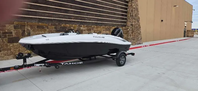 Slide: The Image of 2025 Tahoe T16 boat on trailer, parked near a stone building. - 1