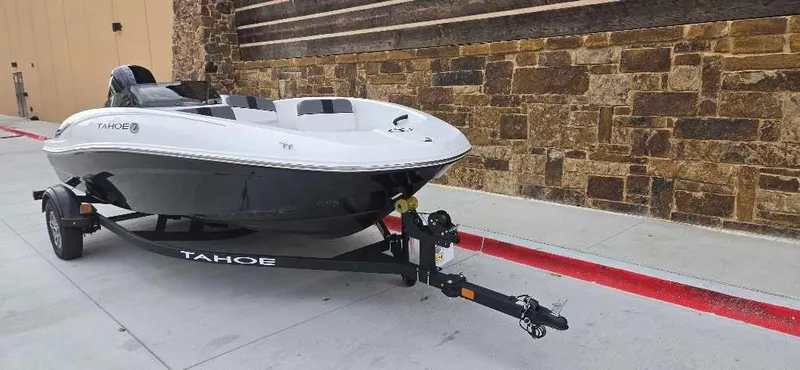 Slide: The Image of 2025 Tahoe T16 boat on trailer, parked by stone wall. - 2