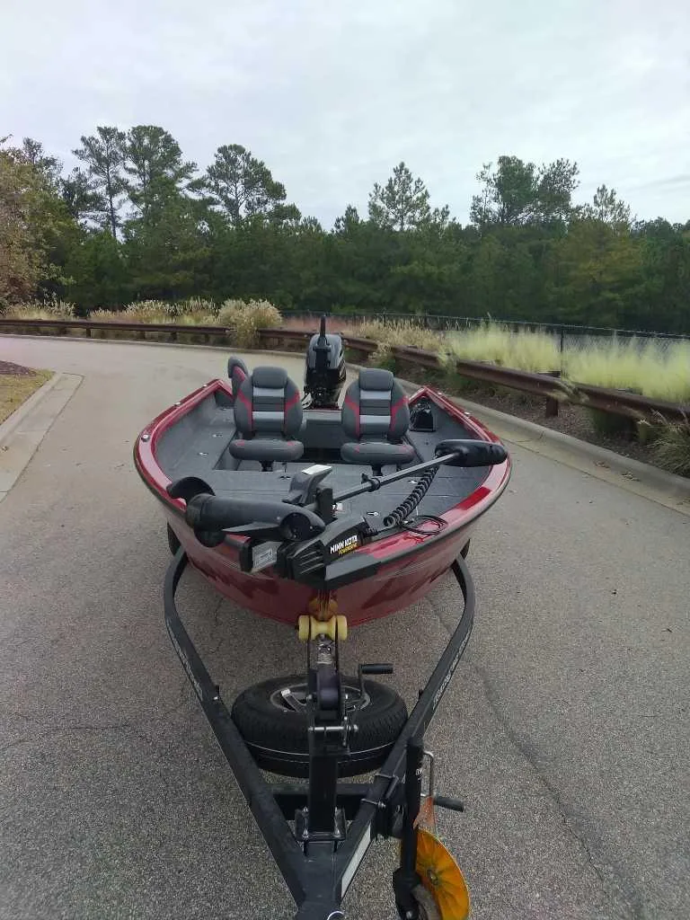 The Image of 2024 Ranger VS1665T boat on trailer, parked on a road with trees in the background. - 0
