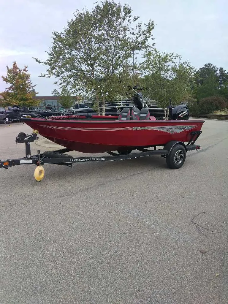 Slide: The Image of 2024 Ranger VS1665T boat on trailer in parking lot, red color. - 2