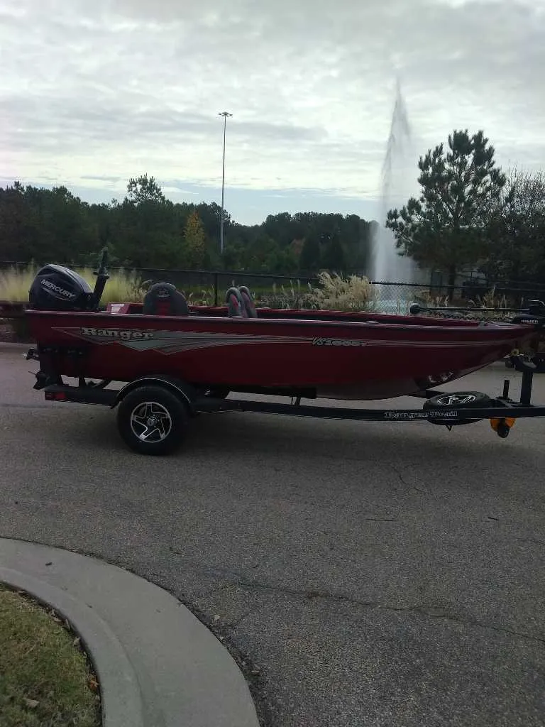 Slide: The Image of 2024 Ranger VS1665T boat on trailer, parked near a fountain and trees. - 4