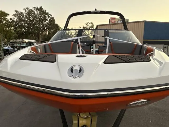 Slide: The Image of 2025 Scarab 195 LX boat on trailer, orange and black design, parked outdoors. - 12