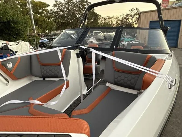 Slide: The Image of 2025 Scarab 195 LX boat interior with orange and gray seating, docked outdoors. - 3
