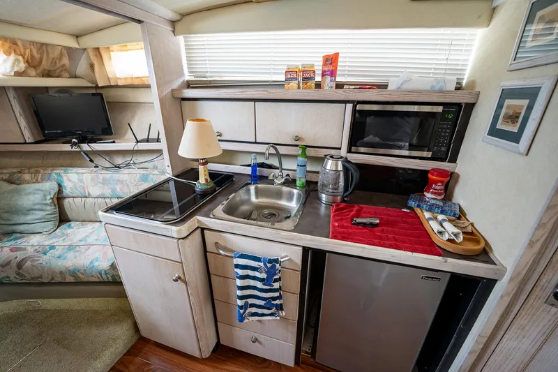 Slide: The Image of Compact kitchen area in a 1997 Bayliner 3255 Avanti boat with sink, stove, and mini-fridge. - 31